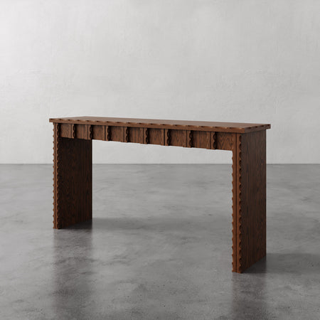 Lemieux et Cie Marchand Console Table in warm oak, console table with scalloped edge detail and three drawers, shown on polished concrete floor against neutral plaster walls.