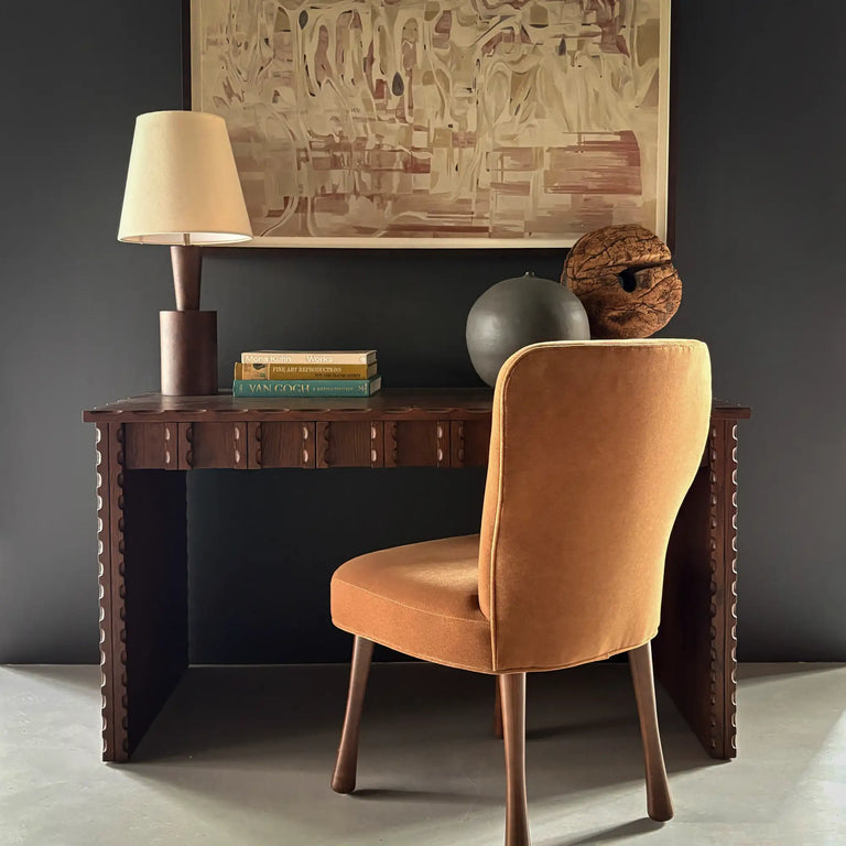 Lemieux et Cie Marchand Desk in walnut oak finish, styled with tapered shade lamp and abstract artwork, dark gray walls in sitting room.