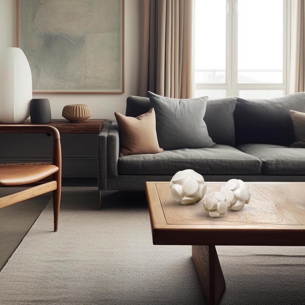 Lemieux et Cie Mayet Sphere Sculpture, geometric orb form in matte white, styled on wood coffee table in a neutral living room with soft daylight.