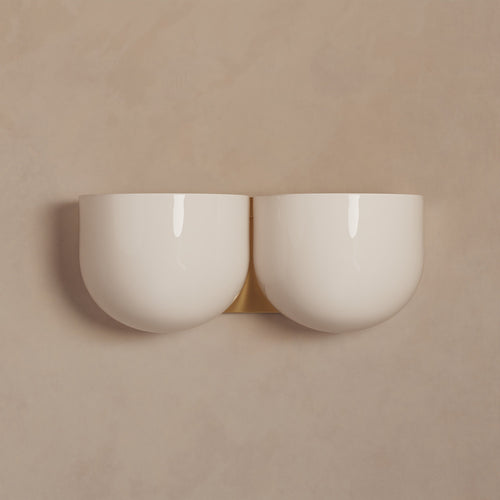 Lemieux et Cie Cheverny Sconce, double bowl-form wall light in ivory with warm brass backplate, mounted on neutral plaster wall.