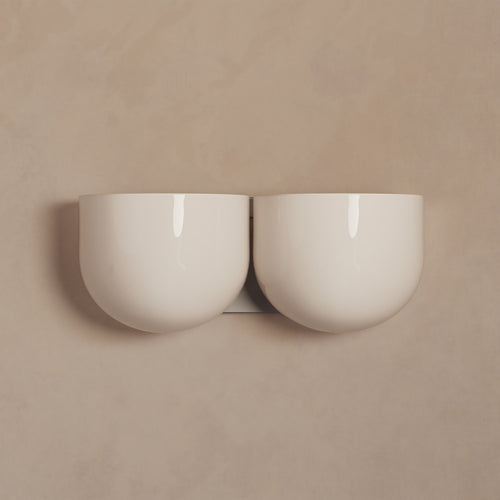Lemieux et Cie Cheverny sconce pair in ivory, rounded bowl forms with polished finish, mounted on neutral plaster wall in soft light.