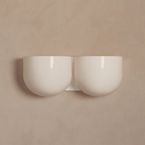 Lemieux et Cie Cheverny sconce, double bowl form in ivory ceramic, wall-mounted on warm neutral plaster backdrop.