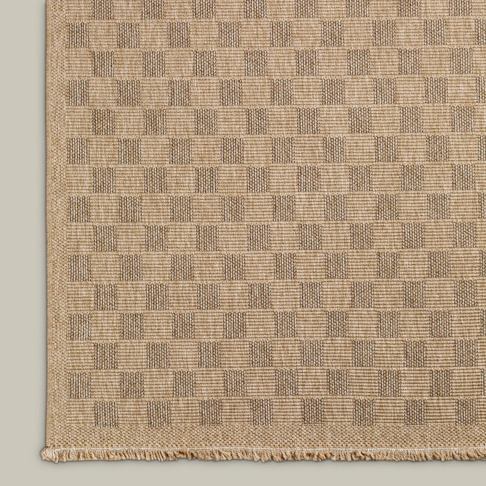 Lemieux et Cie Carreaux Outdoor Rug in natural and brown, geometric checkerboard pattern with textured weave and fringed edge, shown on neutral backdrop.