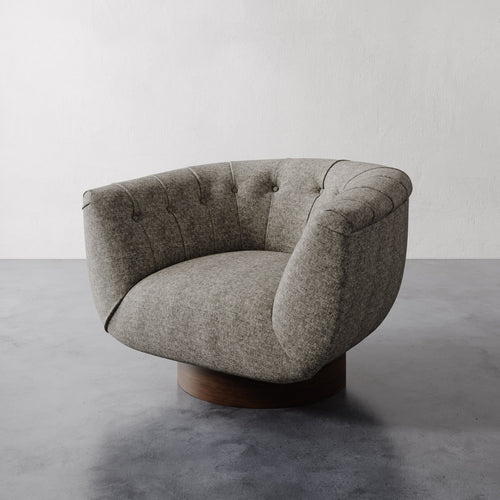 Grey mink linen Lemieux et Cie Lune Swivel Chair with a rounded tufted back and sculptural silhouette against a white wall and gray floor.