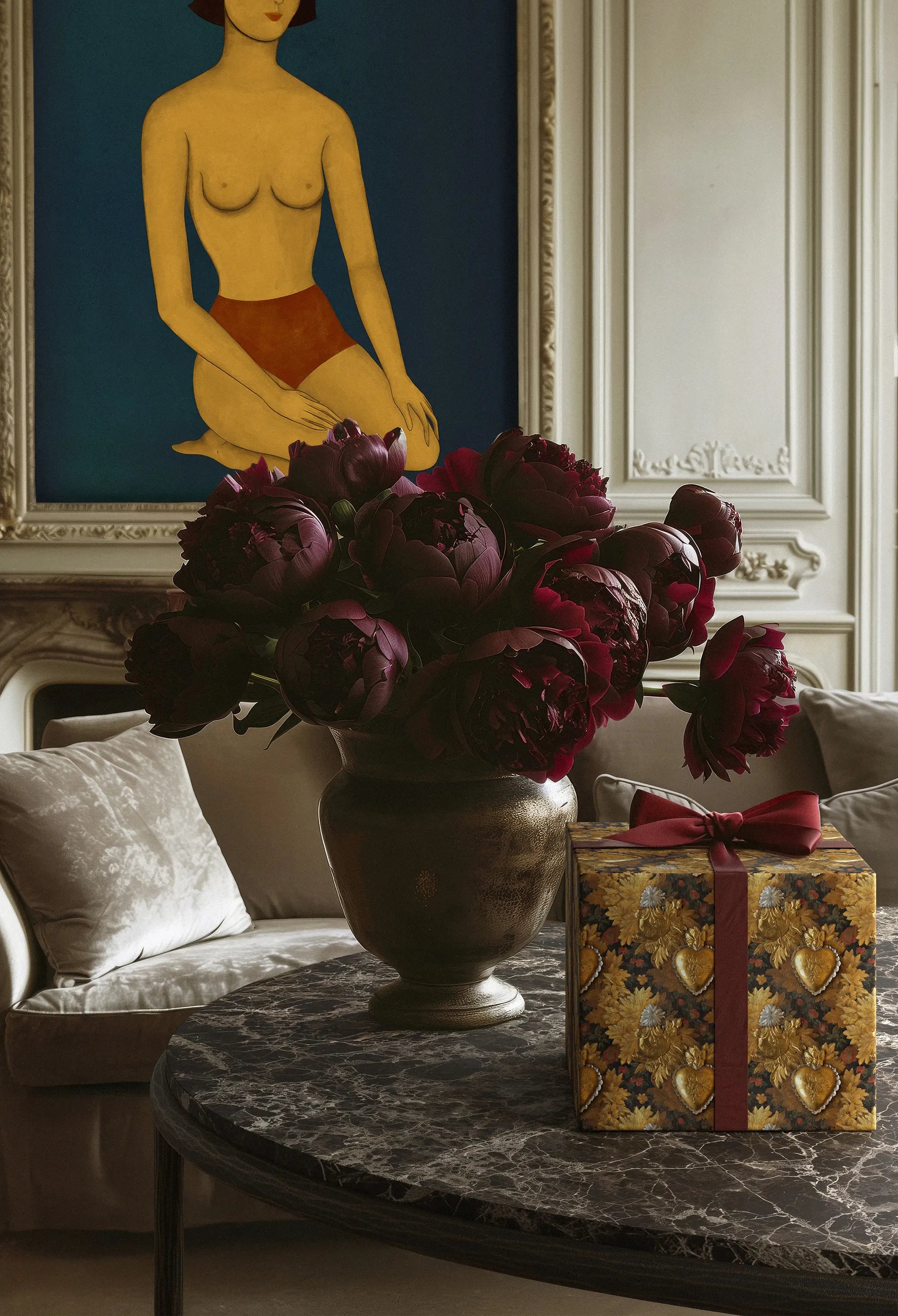 Lemieux et Cie Ravelle Oval Coffee Table in Emperador marble with aged bronze iron frame, styled in a sitting room with white paneled walls and soft daylight.