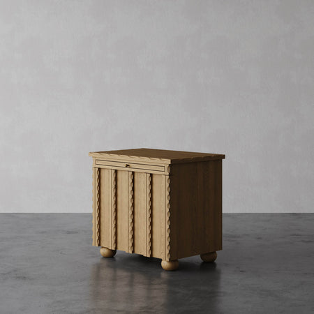 Lemieux et Cie Marchand Nightstand with scalloped edge detailing and textured door fronts, bedside cabinet on rounded feet, shown on polished concrete floor.