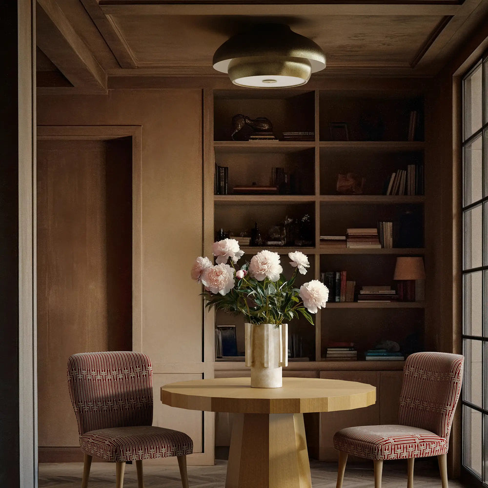 Lemieux et Cie Solene Flush Mount in aged iron with nested dome silhouette, flush mount ceiling fixture hung above a round table in a wood-paneled library with built-in shelving.