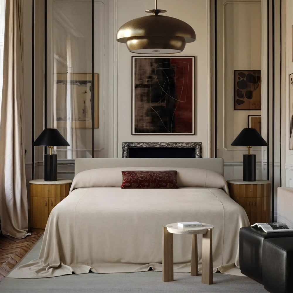 Lemieux et Cie Gérard Bed, low-profile platform bed with wrapped headboard, styled in bedroom with white paneled walls and parquet flooring.