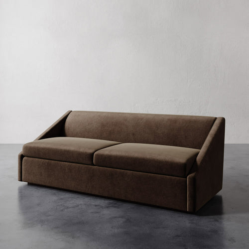 Lemieux et Cie Fontaine Sofa in warm taupe upholstery, sculptural architectural sofa with wrapped arms, shown on concrete floor against white plaster wall.