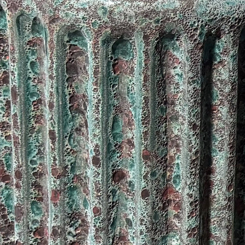 Close up of the Oxidized Jade reactive glaze with fluted ceramic form and aged-metal green and oxblood finish. 