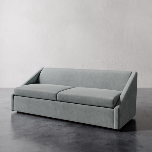 Lemieux et Cie Fontaine Sofa in pale gray upholstery, architectural sofa with structured silhouette, shown on polished concrete floor against textured white walls.
