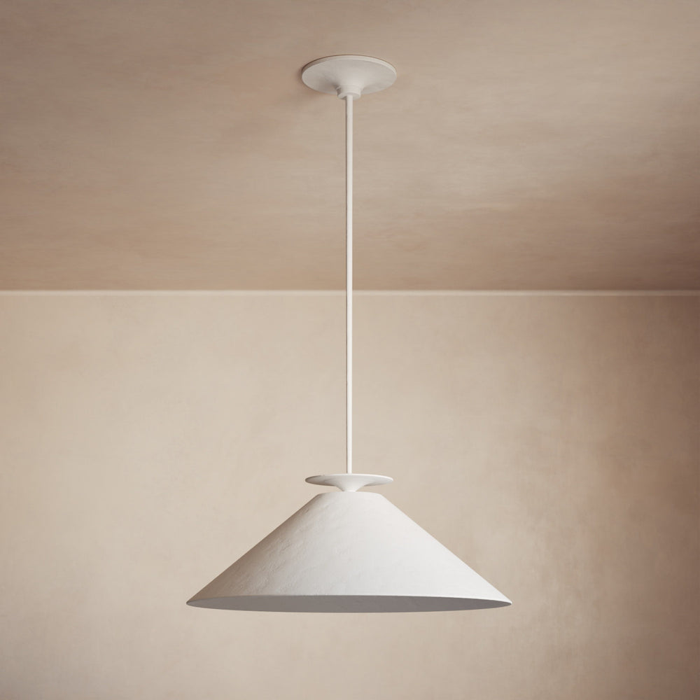 Lemieux et Cie pendant light with conical shade and slim stem, hung in a room with warm blush ceiling and neutral walls.