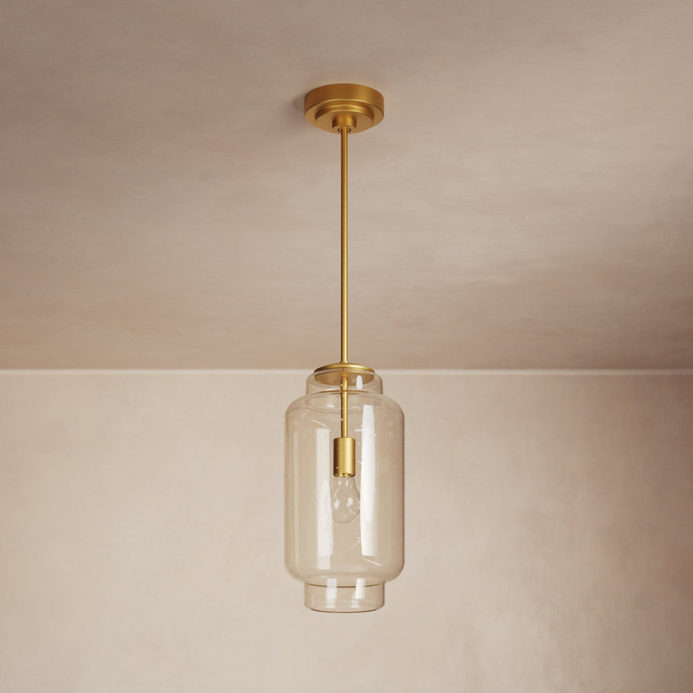 Lemieux et Cie Nodier Pendant, cylindrical glass shade with warm brass hardware, hung from neutral ceiling in soft interior light.
