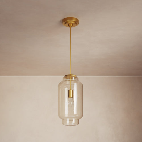 Lemieux et Cie Nodier Pendant, cylindrical glass shade with warm brass hardware, hung from neutral ceiling in soft interior light.
