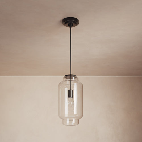 Lemieux et Cie Nodier Pendant, cylindrical glass shade with dark finish canopy, hung in a room with neutral walls and ceiling.