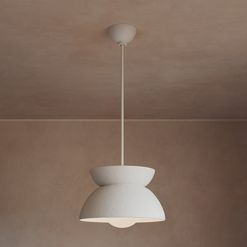 Lemieux et Cie pendant light in ivory with stacked geometric form, suspended in a room with warm plaster ceiling and neutral walls.