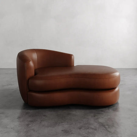 Lemieux et Cie Rulmann Leather Left Arm Chaise in warm tobacco leather, sculptural low-slung chaise on concrete floor against neutral plaster walls.