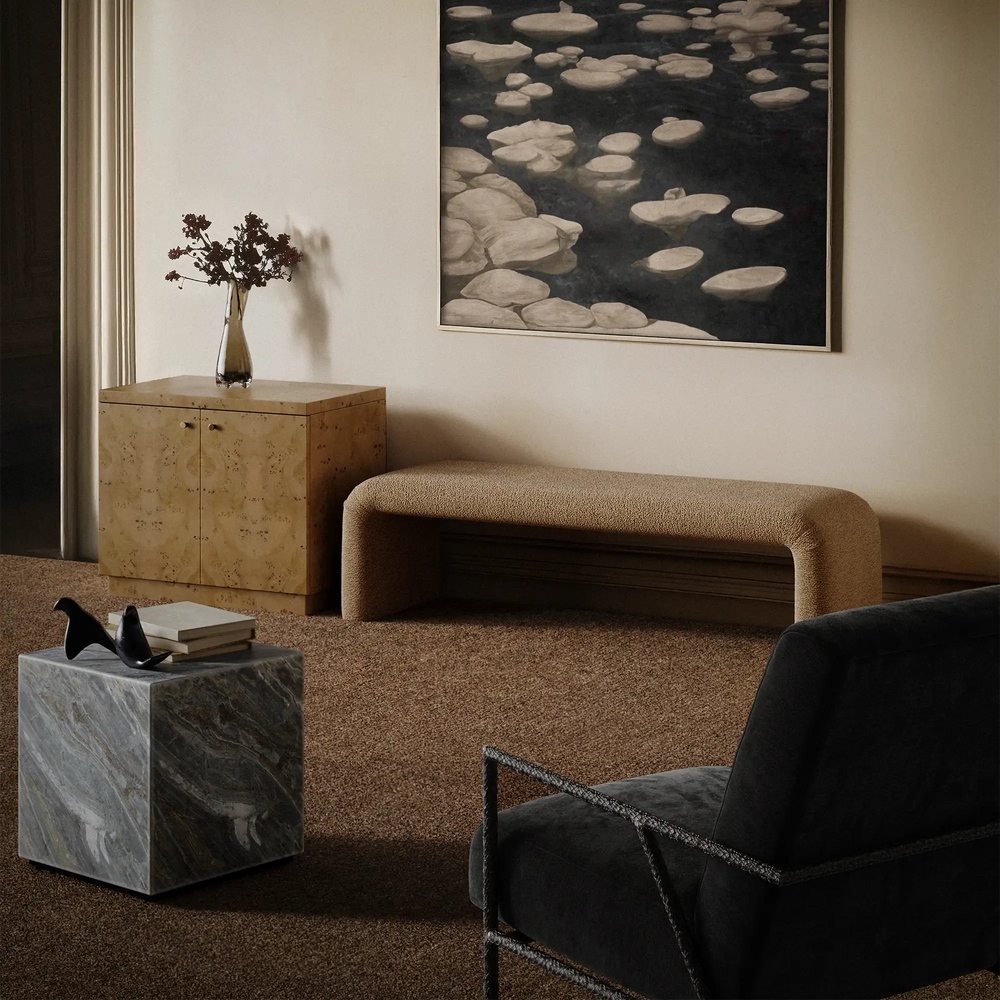 Lemieux et Cie Plume Handmade Wool Rug in Desert Tan, handloomed in India, shown in a neutral-toned sitting room with marble cube table and upholstered bench.