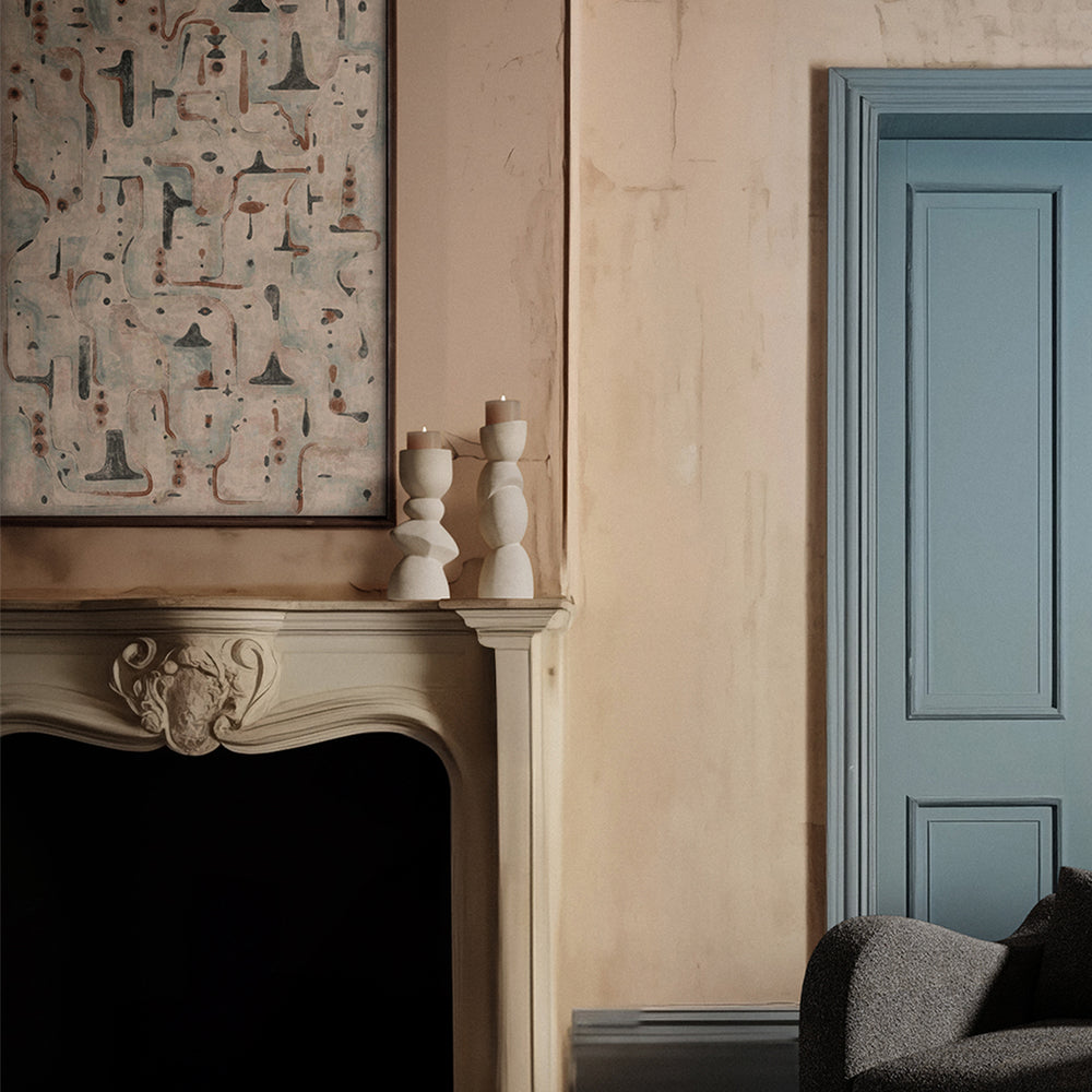 Lemieux et Cie Ramus decorative wall sculpture in wood, brass and iron, diamond-shaped hand-carved relief above a carved mantel in a room with plaster walls and blue paneled door.