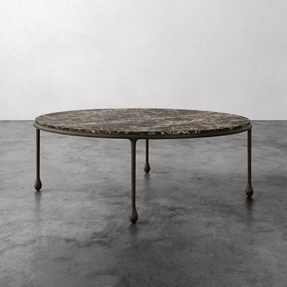 Lemieux et Cie Ravelle Oval Coffee Table in Emperador marble with aged bronze iron frame, low-profile table on polished concrete floor.
