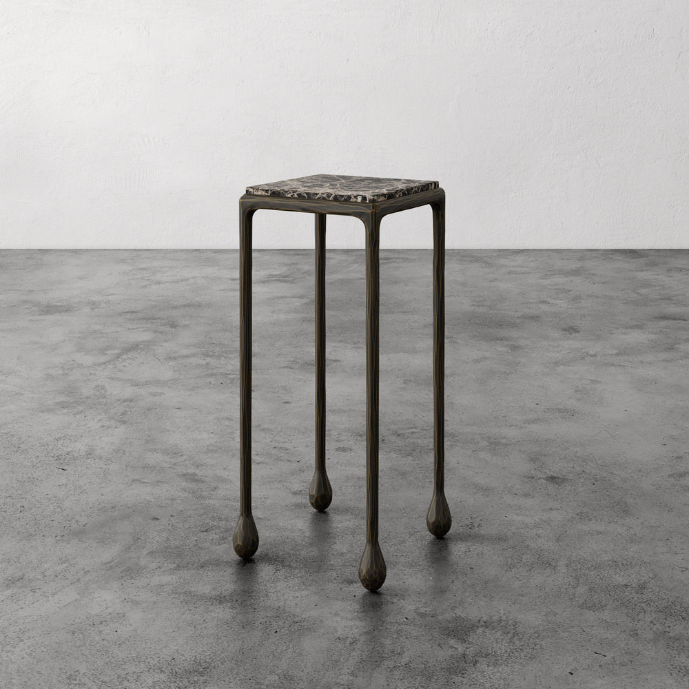 Lemieux et Cie Ravelle Drinks Table in aged bronze iron with honed Emperador marble top, accent table with slender sculpted legs on polished concrete floor.