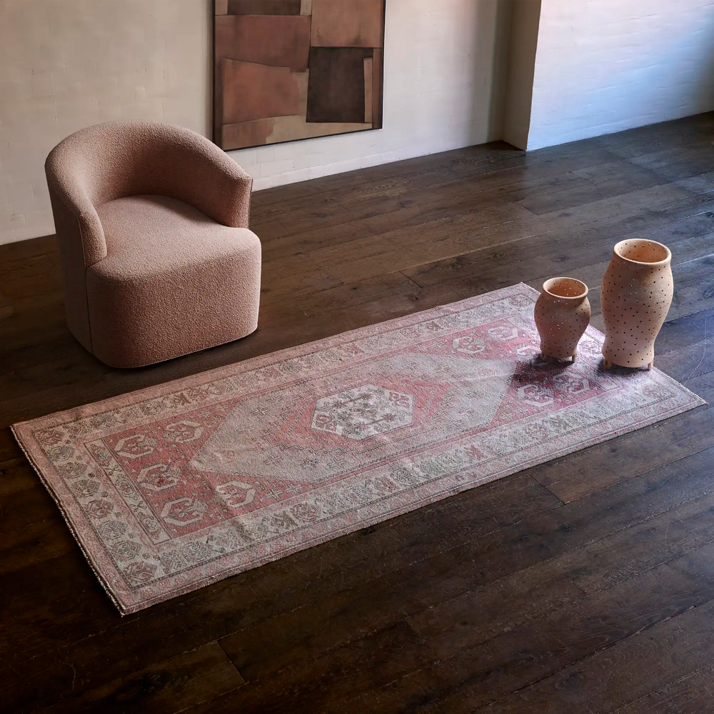 Lemieux et Cie Vintage 1960s Anatolian rug in faded blush and taupe, runner-sized rug on dark wood floors with sculptural chair and ceramic vases.