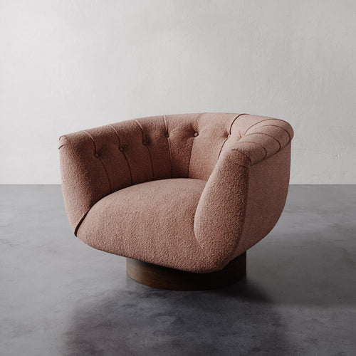 Light pink rosewood berber Lemieux et Cie Lune Swivel Chair with a rounded tufted back and sculptural form against a white wall.