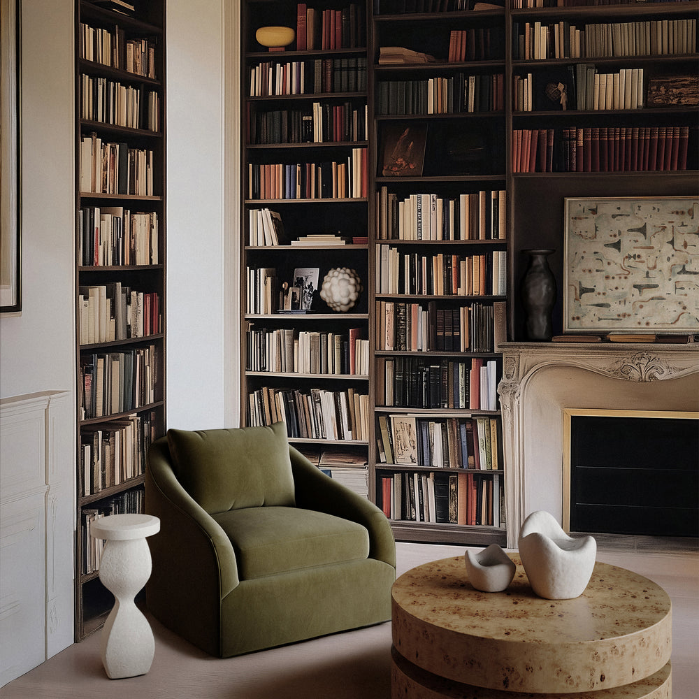 Lemieux et Cie Rousseau Swivel Chair in olive green upholstery, sculptural armchair with rounded arms, styled in a library with floor-to-ceiling bookshelves and carved stone mantel.