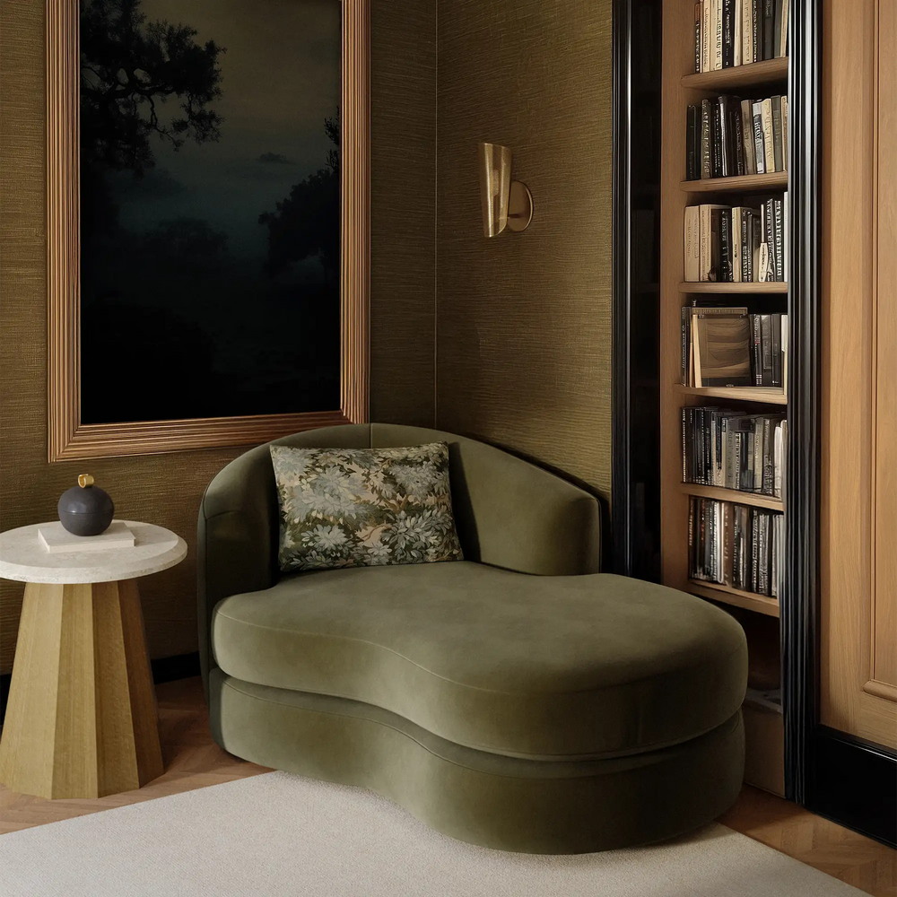 Lemieux et Cie Rulmann Left Arm Chaise in olive green, sculptural curved chaise shown in a reading nook with warm grasscloth walls and wood shelving.