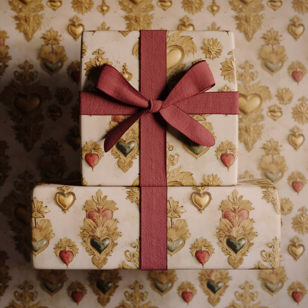 Lemieux et Cie Sacred Heart Gift Wrapping Paper in gold and cream with Victorian heart and floral motif, wrapped gifts with rose ribbon atop matching patterned surface.