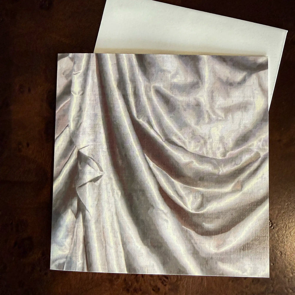 Lemieux et Cie Satin Drape Greeting Card, fine art print of draped fabric in soft ivory tones, shown on dark wood surface.