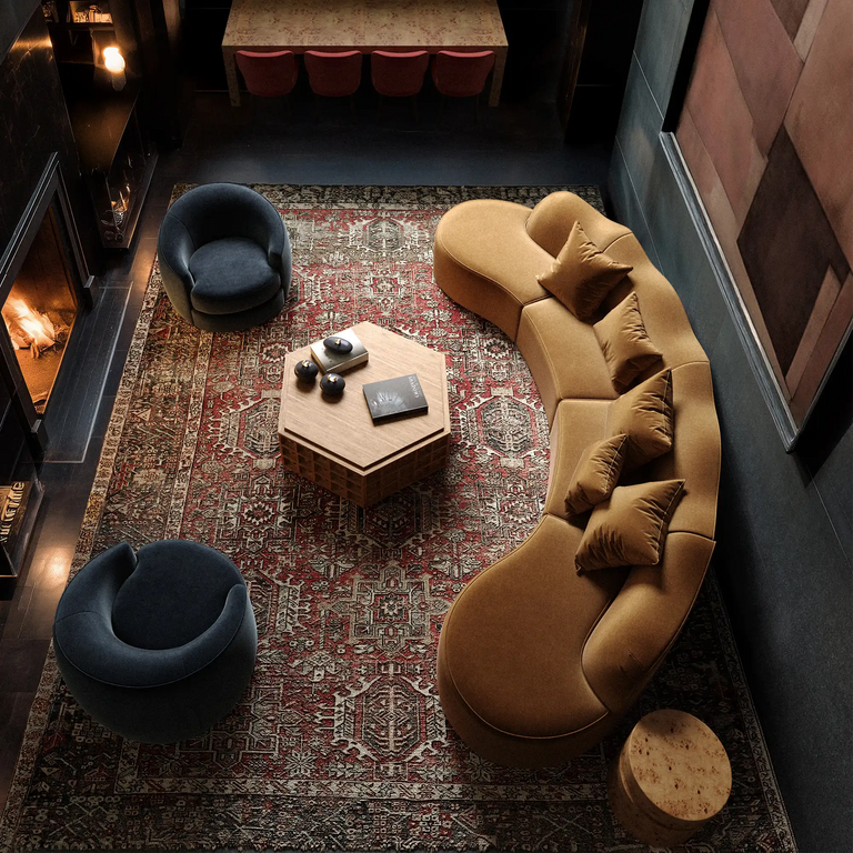 serpentine vintage rug rulmann chair-dubois avenir lehavre rozette chiar Cozy living room with a curved sofa, two blue chairs, and a hexagonal coffee table on a patterned rug.