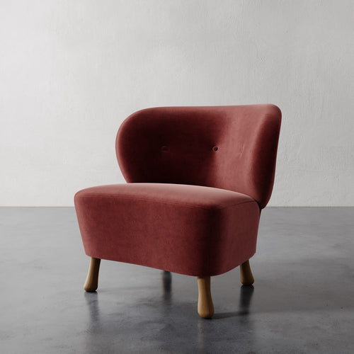 Lemieux et Cie Tourenne Chair with tapered legs, rounded lounge chair with button-tufted back, shown on polished concrete floor against white plaster wall.