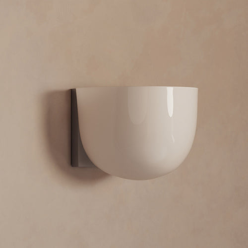 Lemieux et Cie Cheverny Sconce with rounded ceramic shade and dark wall mount, wall-mounted fixture shown against neutral plaster wall in warm light.