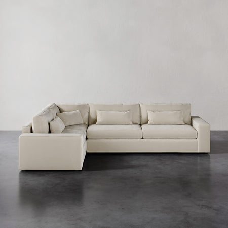 Lemieux et Cie Lacroix Right Arm Sectional in ivory, low-profile modular sofa with bolster pillows, shown on dark concrete floor against neutral walls.