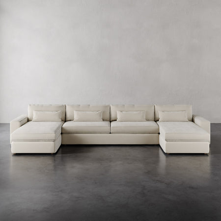Lemieux et Cie Lacroix Sofa U-Sectional in ivory with double chaises, low-profile modular seating on polished concrete floor with neutral plaster walls.