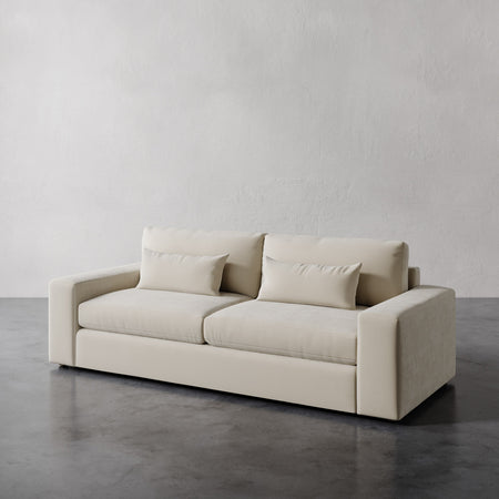Lemieux et Cie Lacroix Sofa in warm neutral upholstery, low-profile sofa with rectilinear form, shown on polished concrete floor against textured plaster wall.