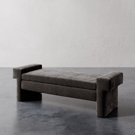 Lemieux et Cie Lemaire Bench with cylindrical bolster arms, low-profile cushioned bench shown on concrete floor against textured plaster walls.