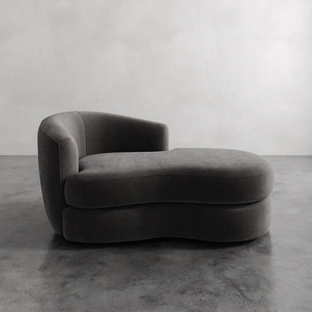 Lemieux et Cie Rulmann Left Arm Chaise, sculptural low-slung chaise with curved back and rounded cushion, shown on polished concrete floor against neutral walls.