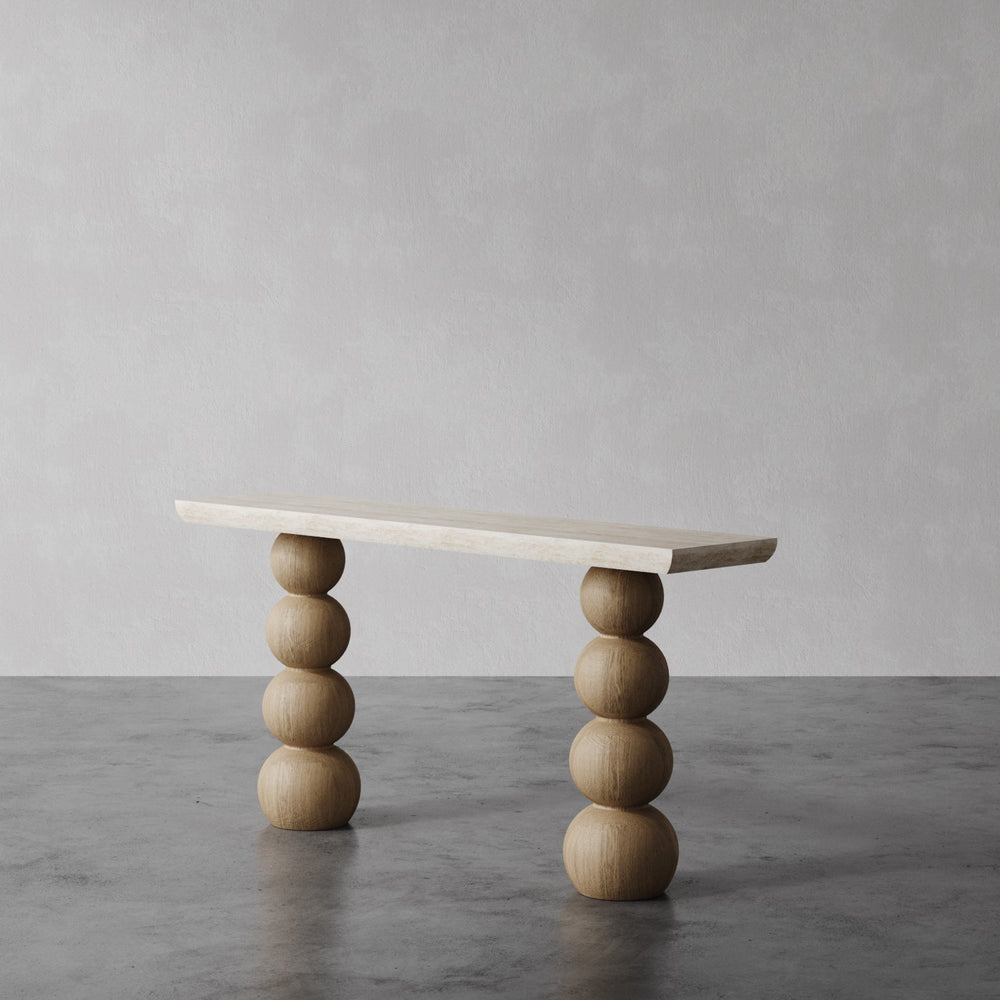 Lemieux et Cie Chloé Console Table, sculptural stacked sphere base supporting rectangular top, shown on polished concrete floor against neutral plaster wall.