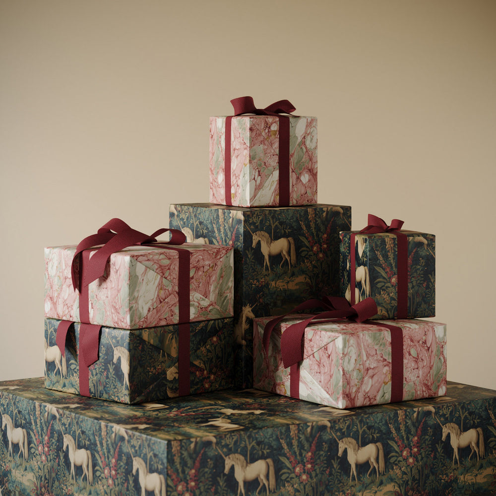 Stack of gifts wrapped in Lemieux et Cie premium wrapping paper: Rosso Portogallo marbled pattern with gold and Unicorn Christmas wrapping paper