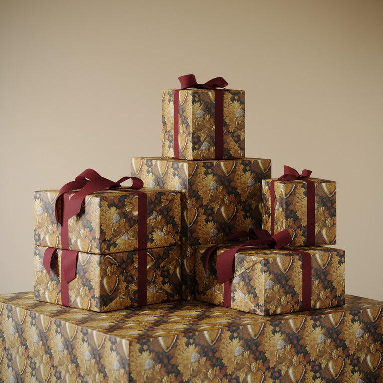 Stack of gifts wrapped in Lemieux et Cie premium wrapping paper: Victorian Locket a fancy gold pattern combining vintage jewelry and floral motifs
