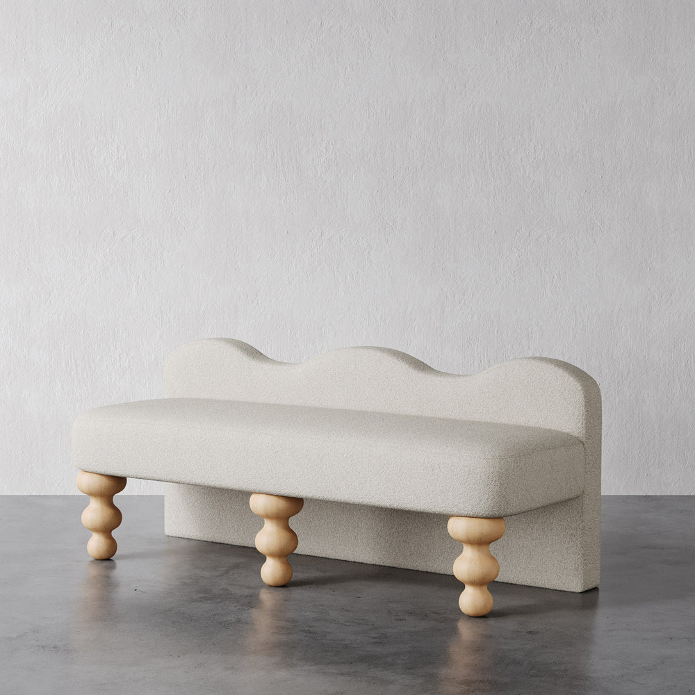 Lemieux et Cie Celine Bench with sculptural scalloped backrest and turned legs, low-profile seating shown on polished concrete floor against textured plaster walls.