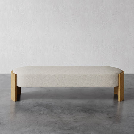 Lemieux et Cie Benoit Bench with rounded upholstered seat and curved corners on polished concrete floor against textured white plaster wall.