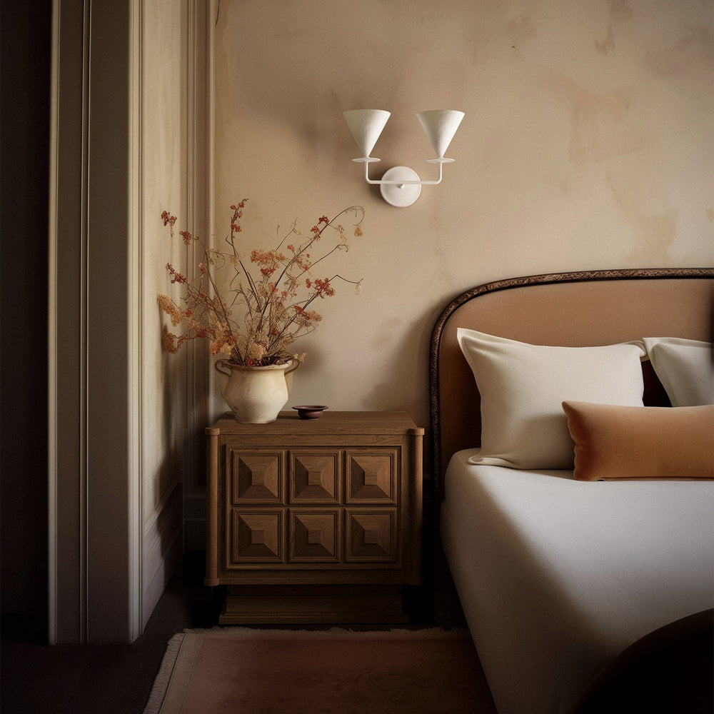 Lemieux et Cie Voltaire Nightstand with geometric paneled drawers, styled bedside with warm plaster walls and upholstered headboard in soft light.