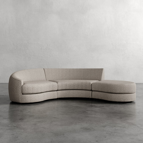 Beige curved sofa on a gray floor with a plain white wall background Rulmann 3-Piece Left Sectional Washed Linen Mink