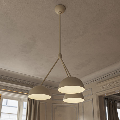 Lemieux et Cie Beaunay Medium Chandelier, a designer lighting fixture in steel and cast plaster with three bowl-shaped shades, casting a warm glow in a softly dim living room with beige walls