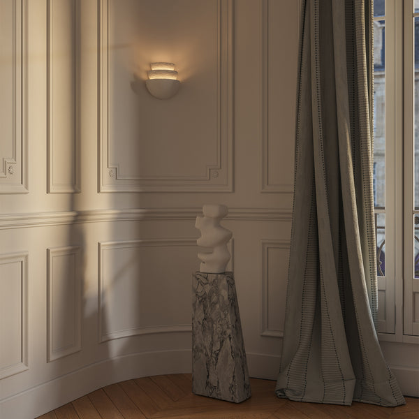 Lemieux et Cie Beaunay Tiered Sconce, a designer lighting fixture in cast plaster with layered bowl-shaped shades on a plaster wall in a European-style room with soft curtains.