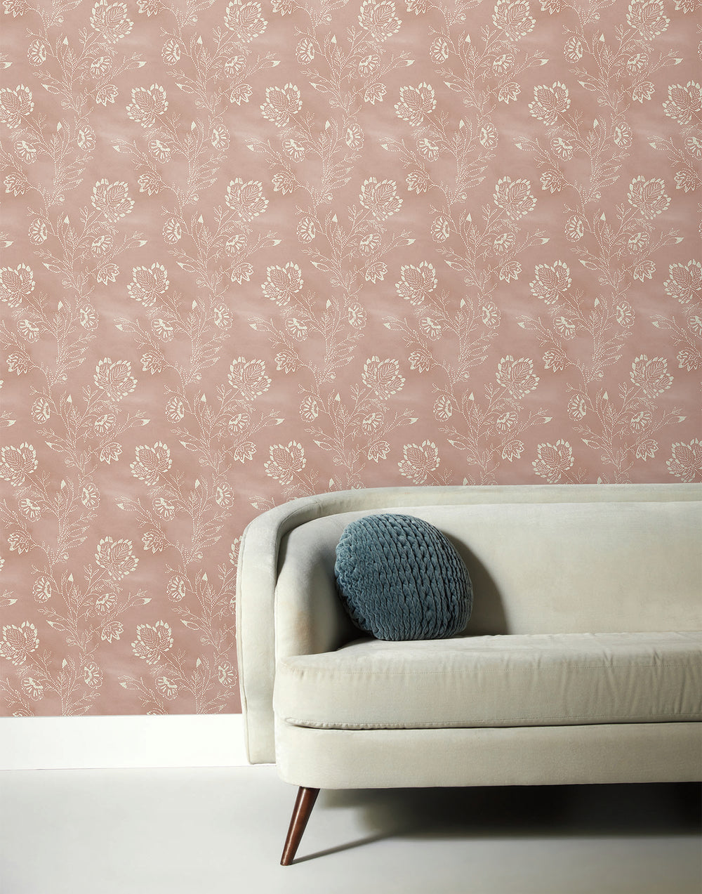 Lemieux et Cie oval cocktail table in cerused European oak with tapered legs, shown beside an upholstered sofa against blush floral wallpaper.