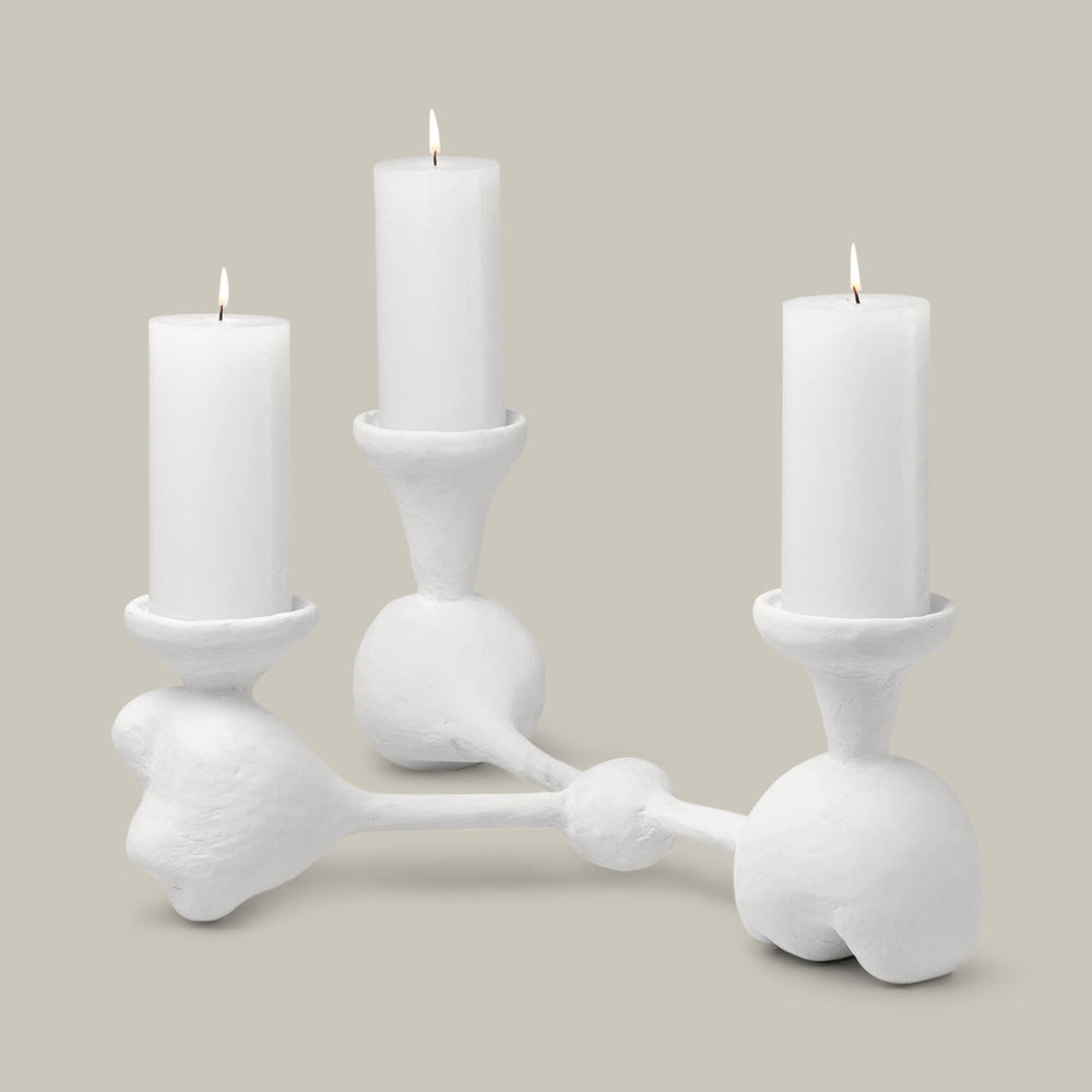 Lemieux et Cie Nunez Modern Candelabra, sculptural three-arm candleholder with organic rounded forms, shown with lit white candles on neutral backdrop.